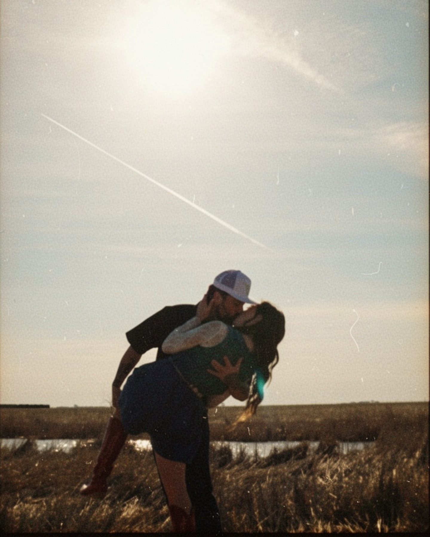 Couple sharing a dip kiss at sunset beside the water