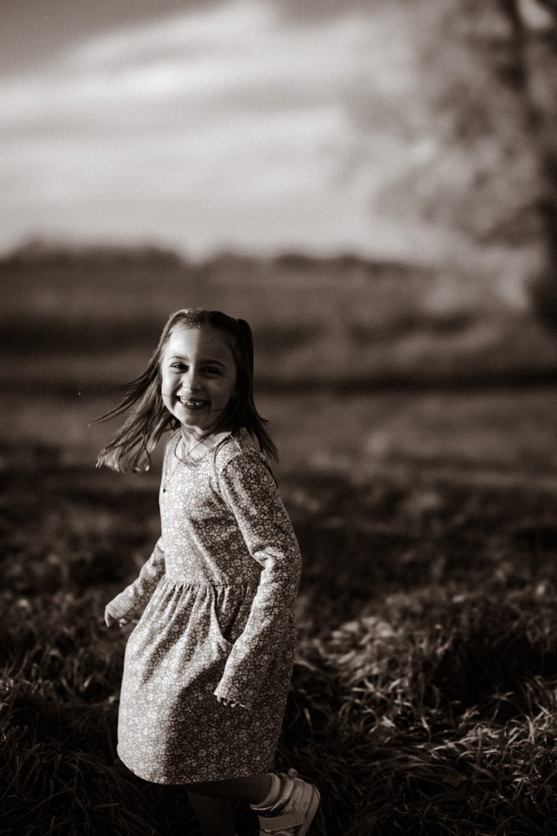 Little girl twirling in her dress in a black and white field portrait