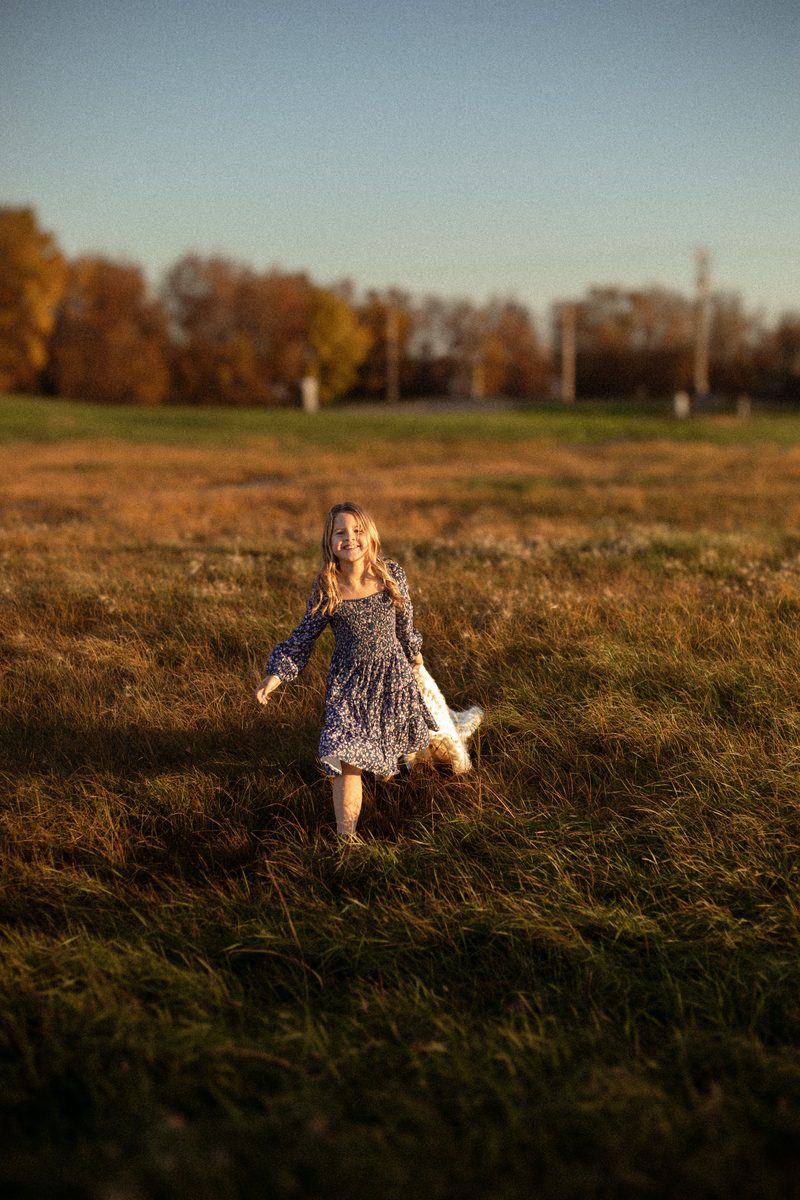 Little girl running through a golden field at sunset