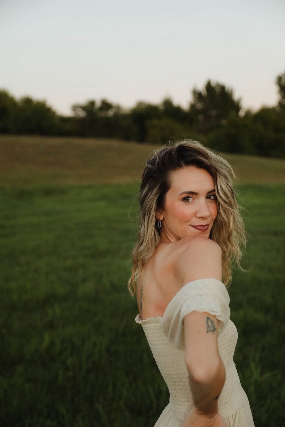 Niki of Mobile Edits smiling over her shoulder in a summer field