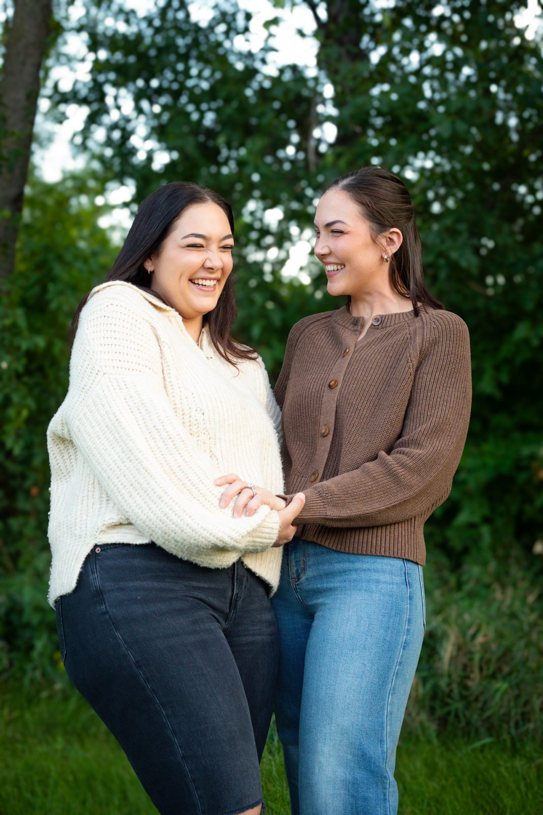 Two sisters laughing together in a green summer park