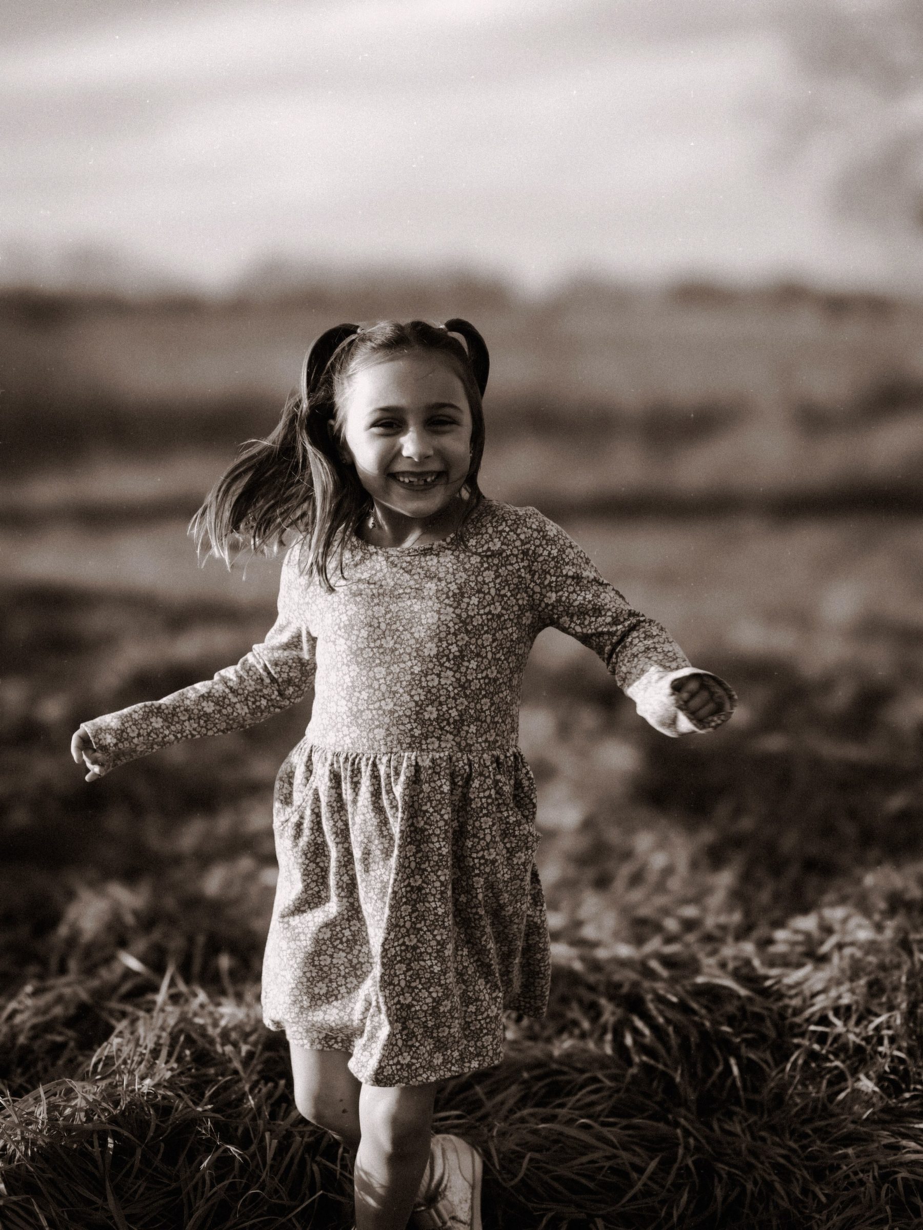 Joyful little girl running in an open field, black and white