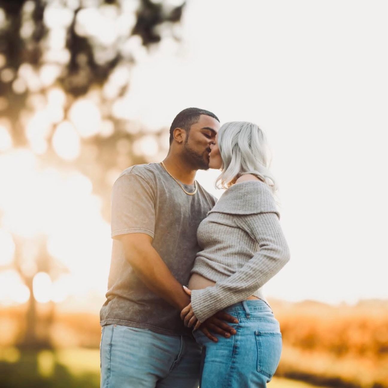 Couple sharing a kiss in a backlit golden hour field