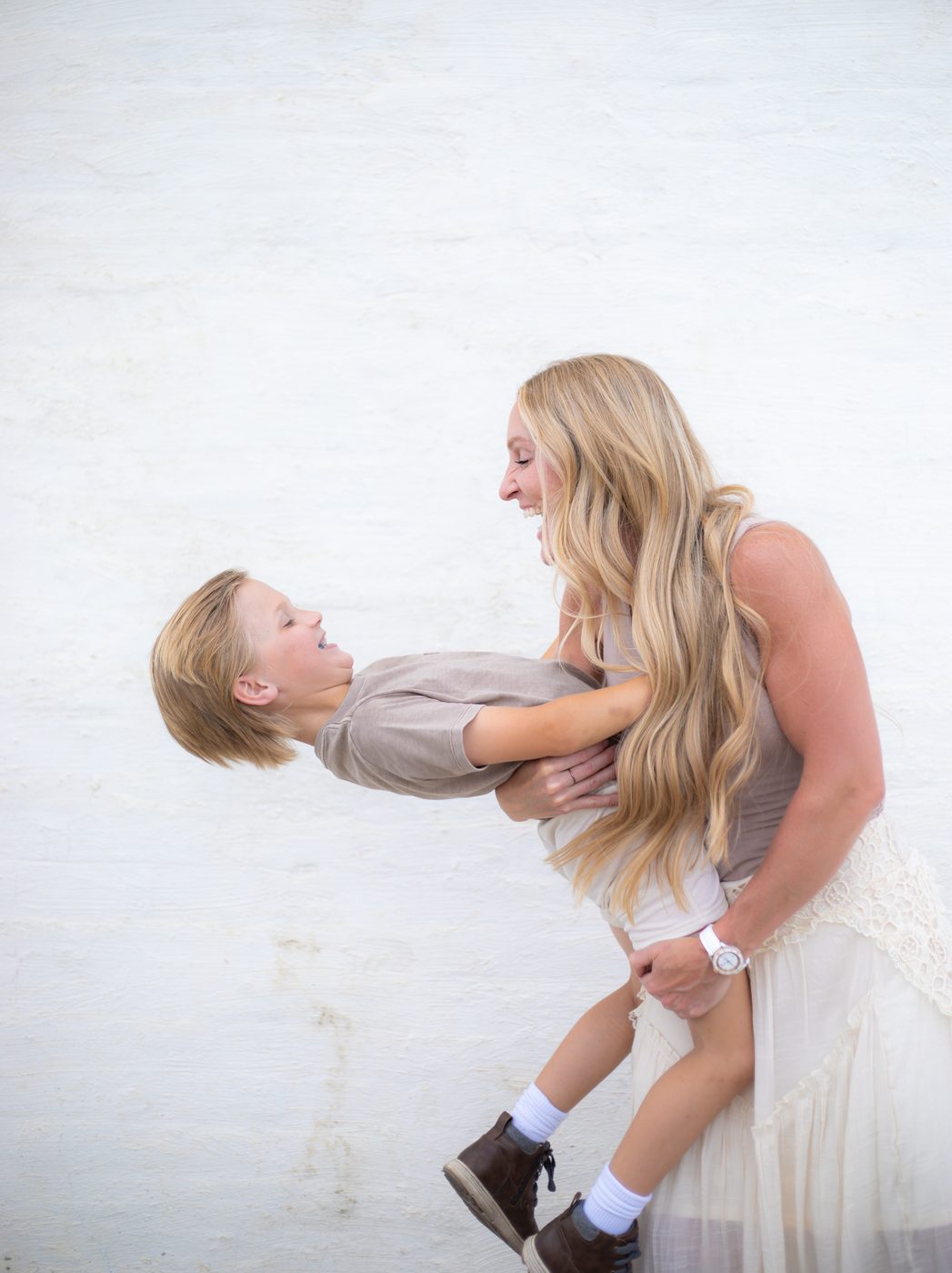 Mother swinging her little boy and laughing