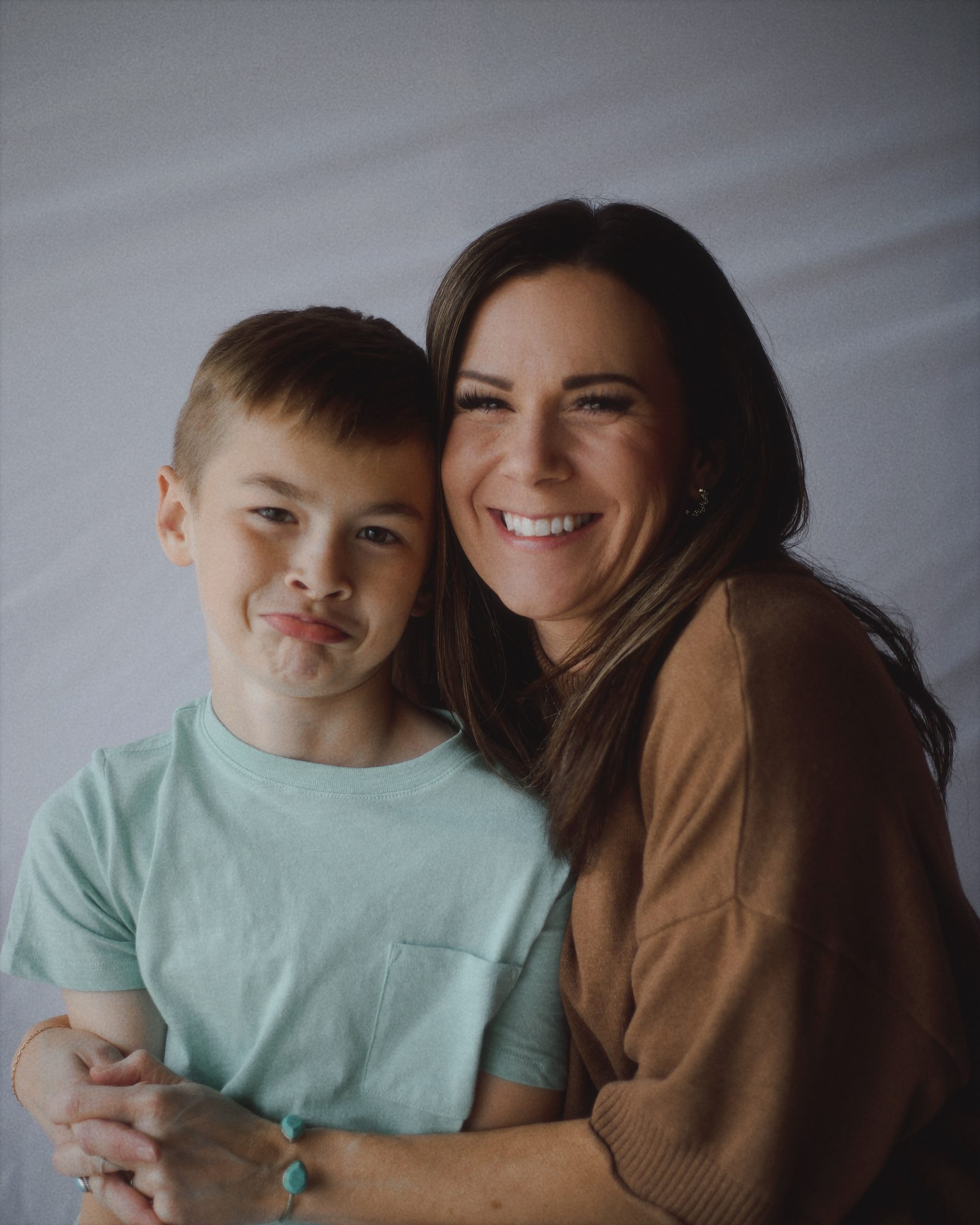 Mother and son smiling cheek to cheek during a portrait session