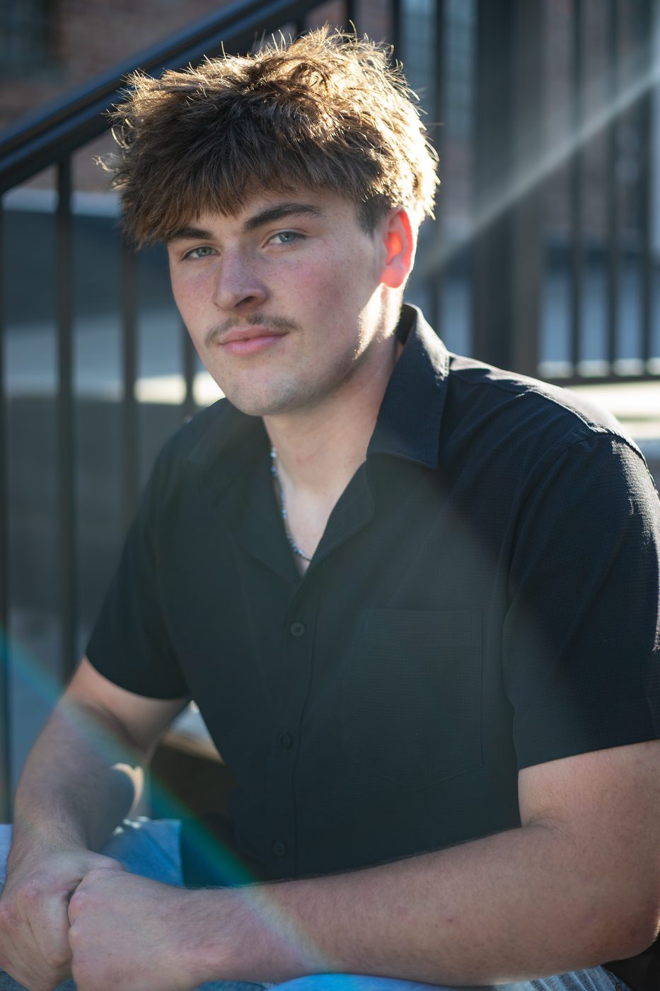 High school senior guy sitting on steps at golden hour