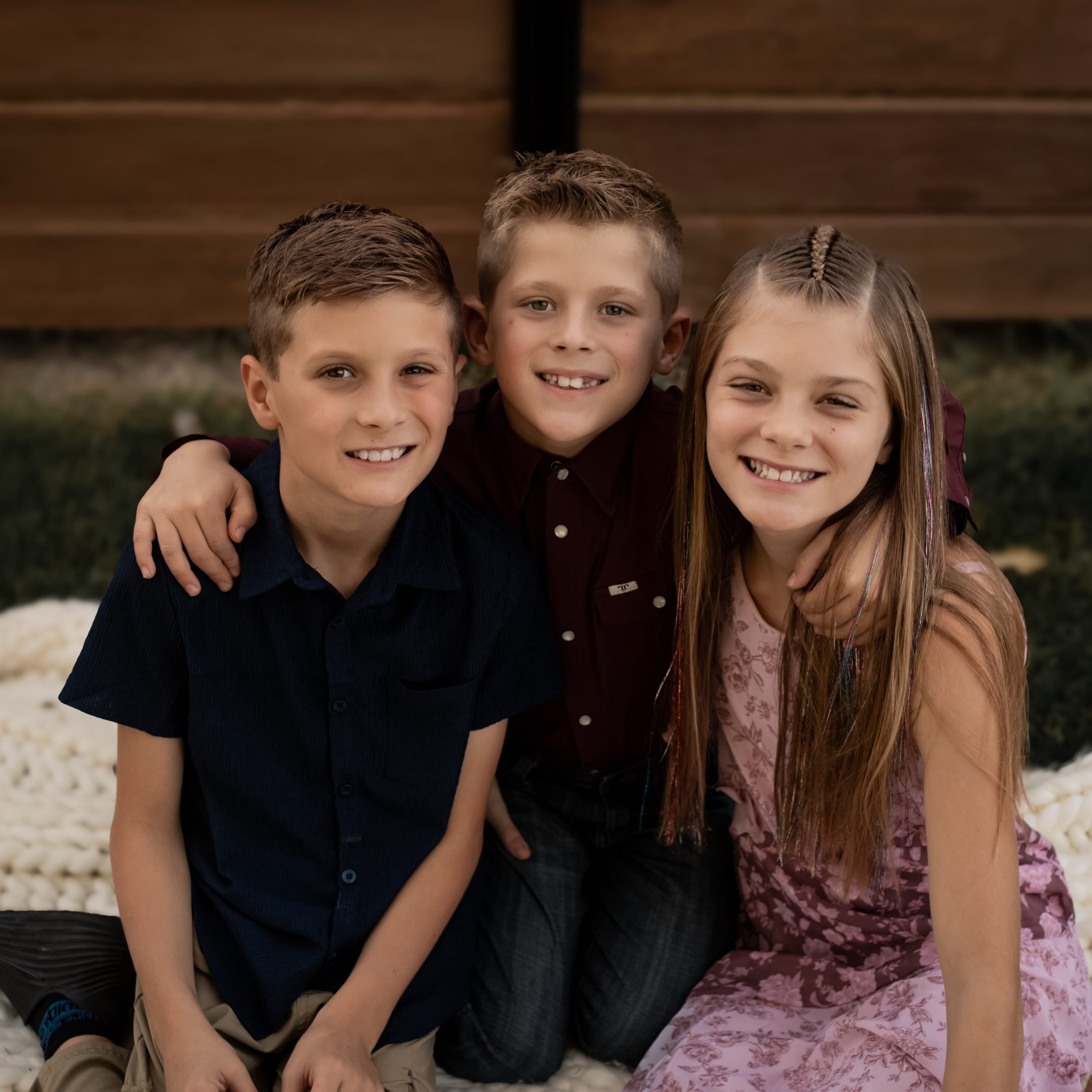 Three siblings smiling together during a backyard session